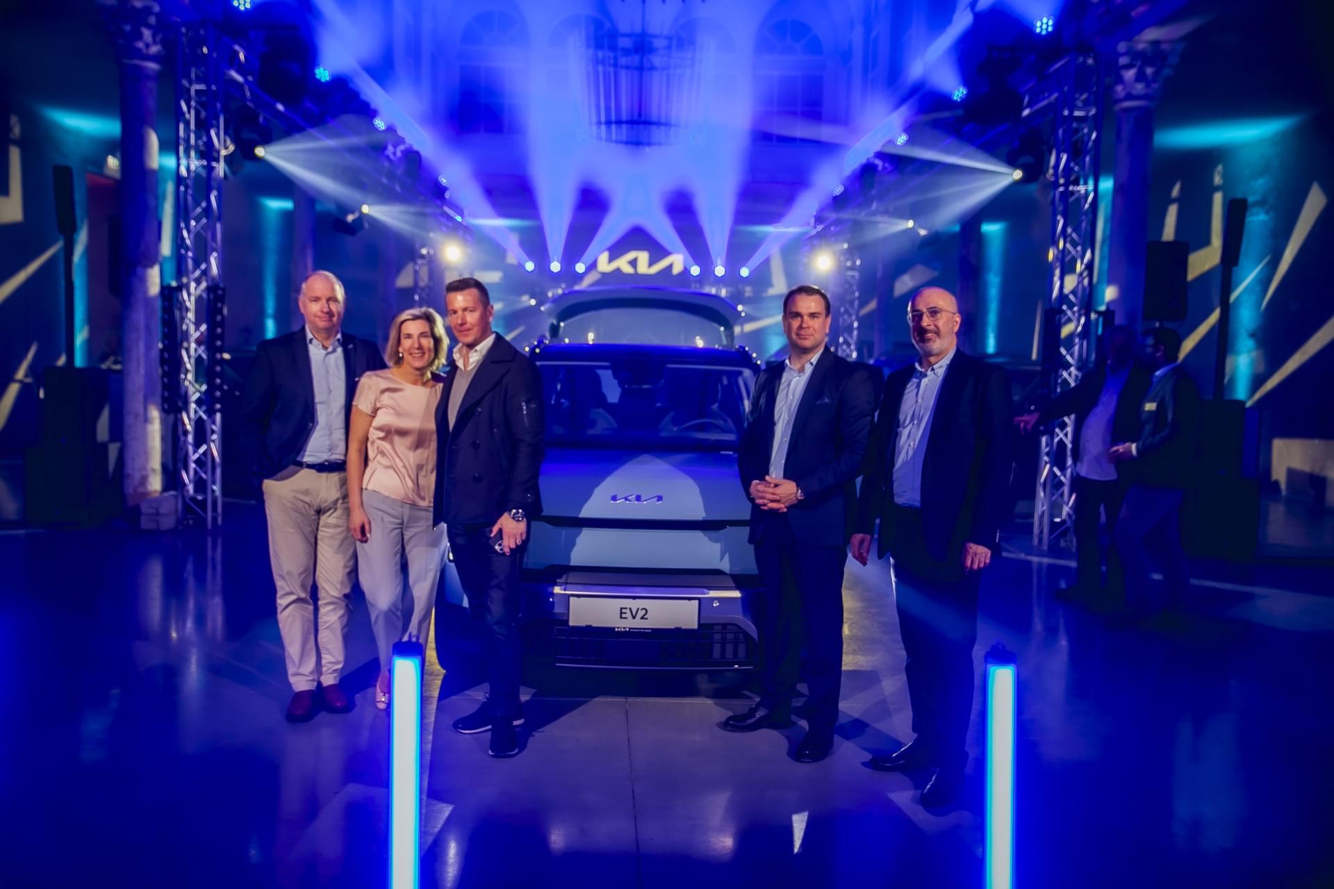 Eine Gruppe von Personen steht vor einem Auto.