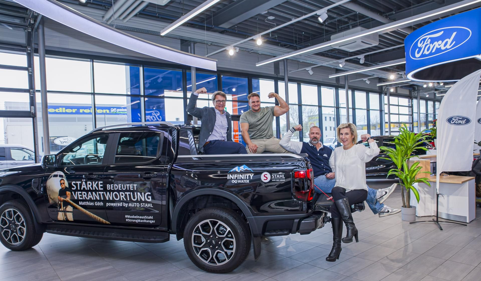Eine Gruppe von Menschen sitzt auf der Ladefläche eines schwarzen Trucks.
