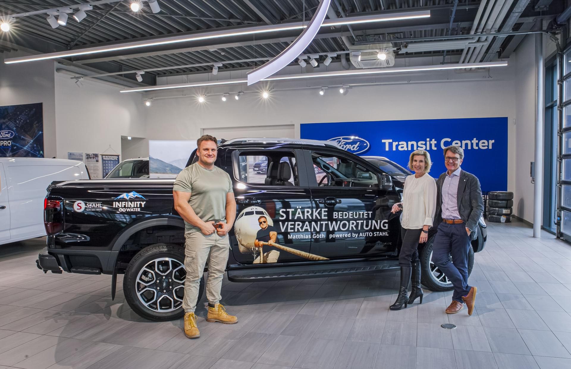 Eine Gruppe von Personen steht neben einem schwarzen Lastwagen.