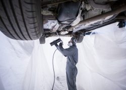 Daniel Bertleff bei der Unterbodenschutzversiegelung eine s Fahrzeuges in der Spenglerei bei AUTO STAHL Wien 22